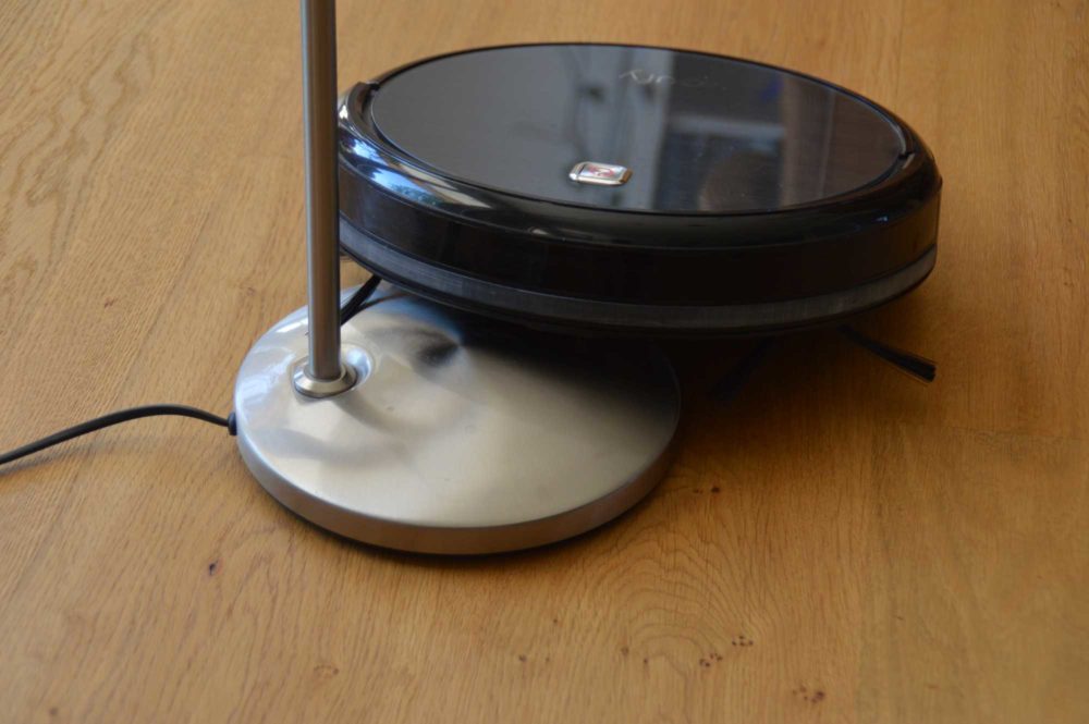 Staubsaugerroboter am Stehlampen-Fuß